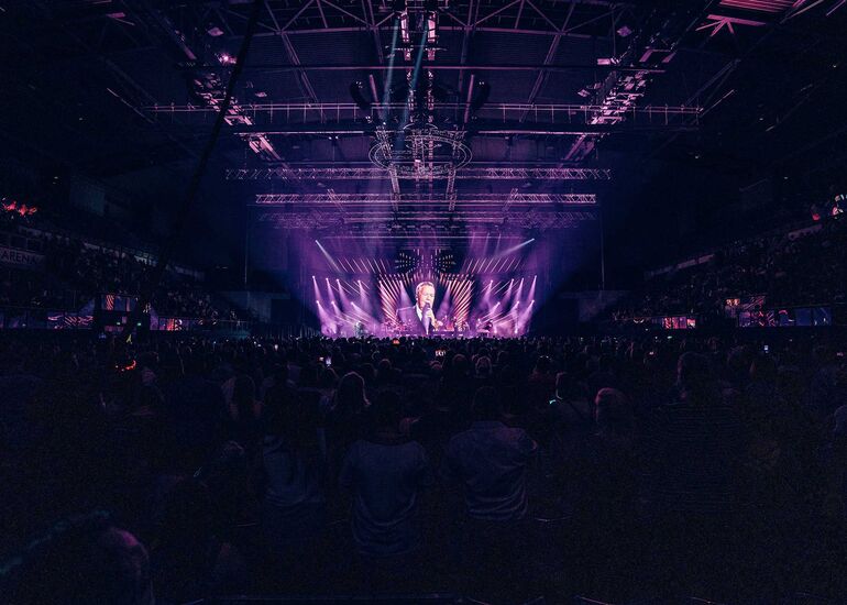 Roland Kaiser gibt ein Konzert in der GETEC-Arena. Das Publikum ist von hinten zu sehen und das Bild erscheint in violetten Farben